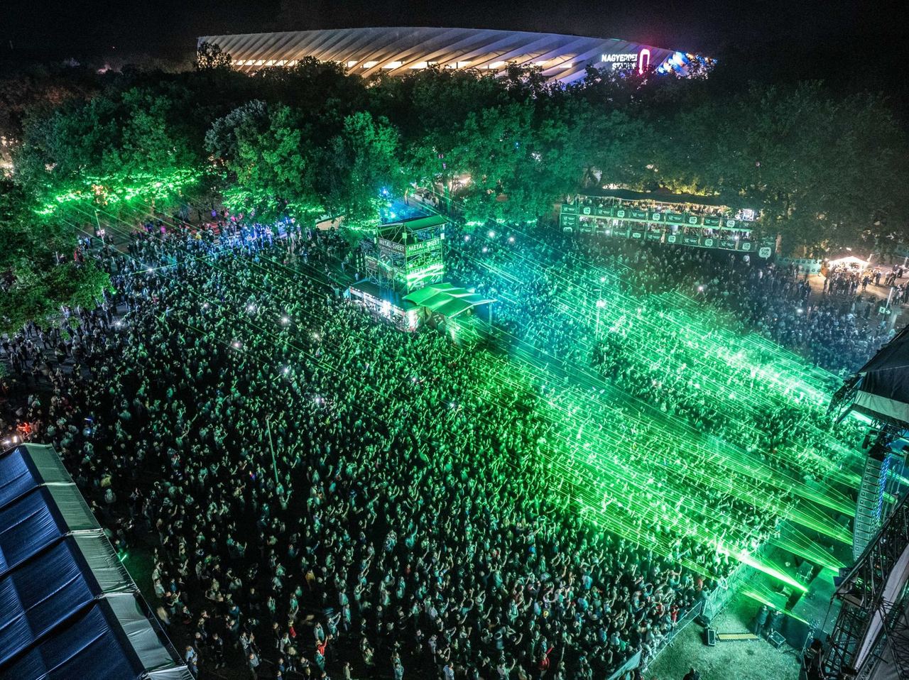 Aerial view of a festival crowd under green lasers